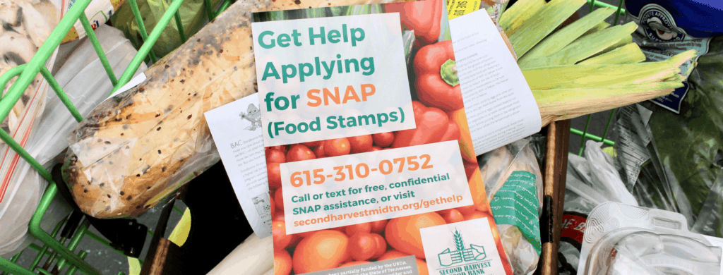 A flyer about SNAP (food stamps) help rests on groceries in a cart, with text offering confidential assistance and a phone number for the Second Harvest Food Bank of Middle Tennessee.