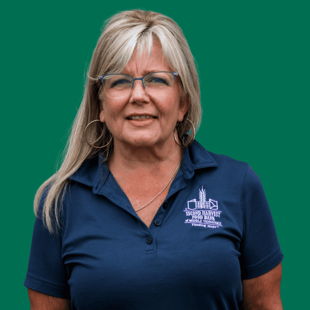 A woman with long blonde hair and glasses, wearing a navy blue collared shirt with the Second Harvest Food Bank logo, stands against a solid green background.