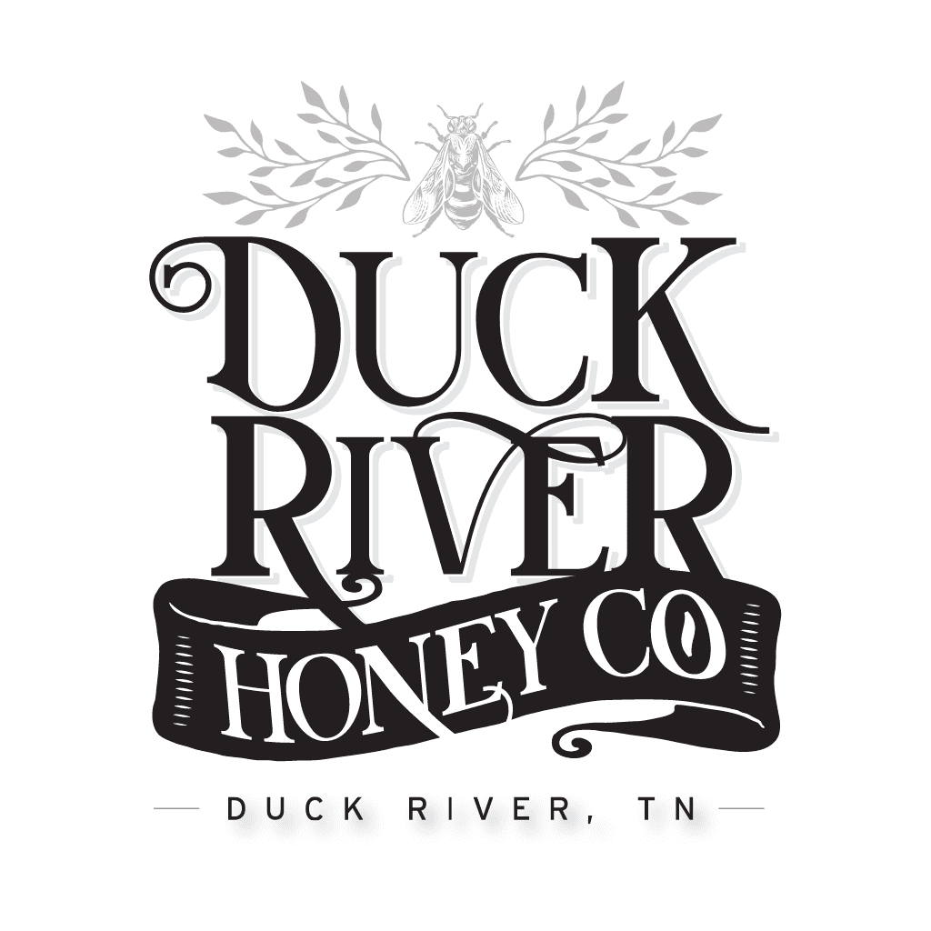 Logo for Duck River Honey Co. featuring a bee and leafy branches above bold, decorative text. A banner below reads Honey Co, with Duck River, TN at the bottom. Black and white design.