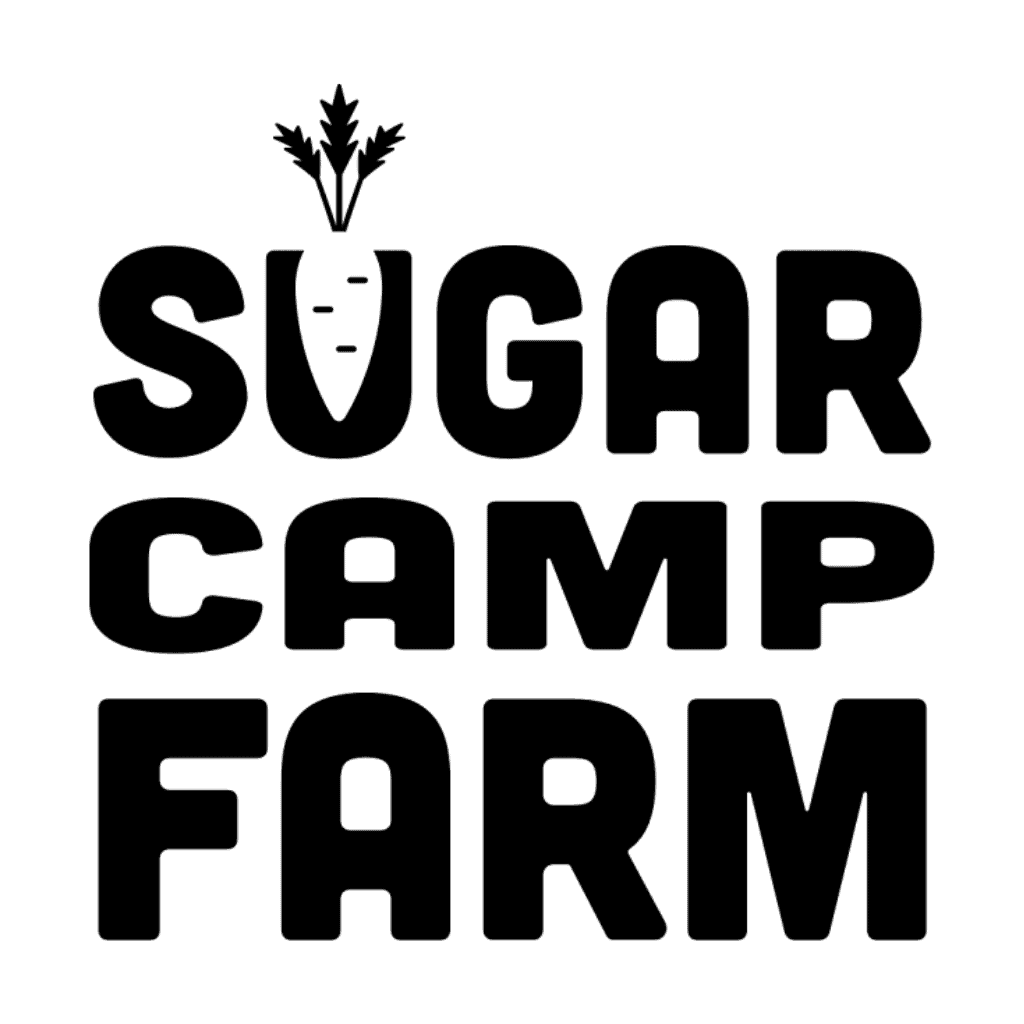 Black text logo reads Sugar Camp Farm with a white carrot replacing the “U” in “Sugar.” The carrot has leafy greens on top, and the text is in bold, uppercase font on a white background.