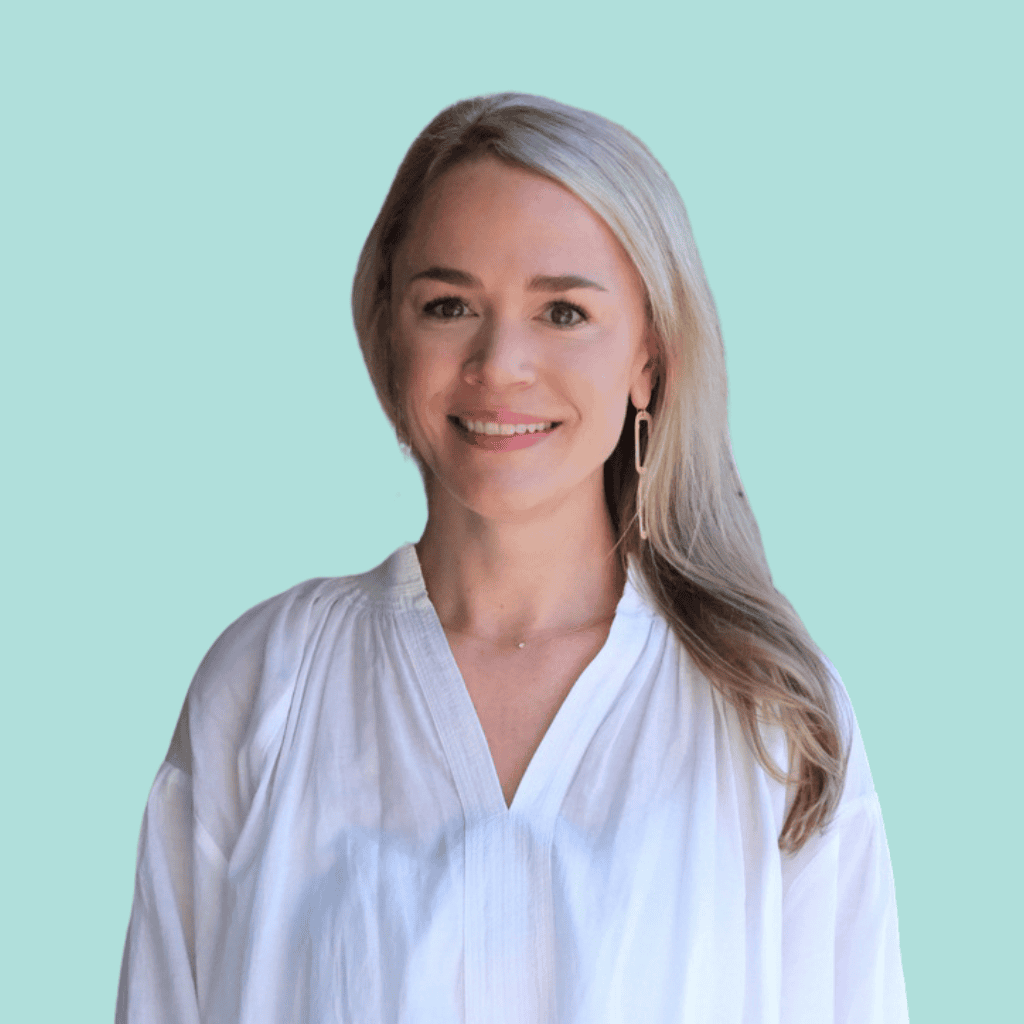 A woman with long blonde hair wearing a loose white blouse smiles at the camera. The background is a solid light teal color.
