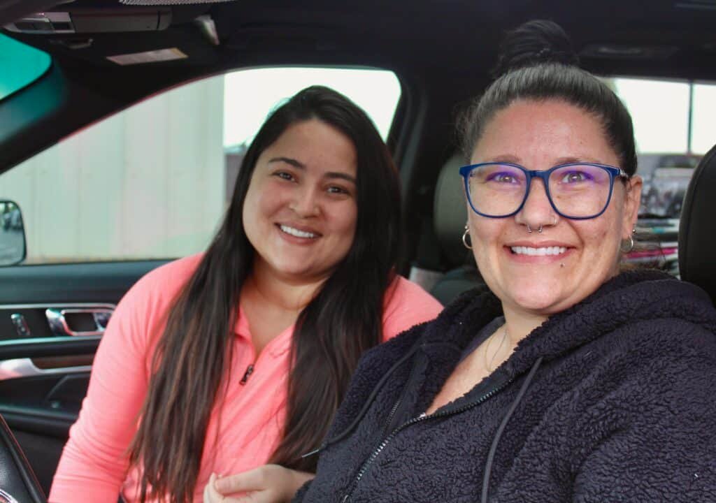 Stephanie and her daughter smile from their car after receiving healthy food to support eating healthy on a budget for blood pressure control at a Second Harvest food distribution.