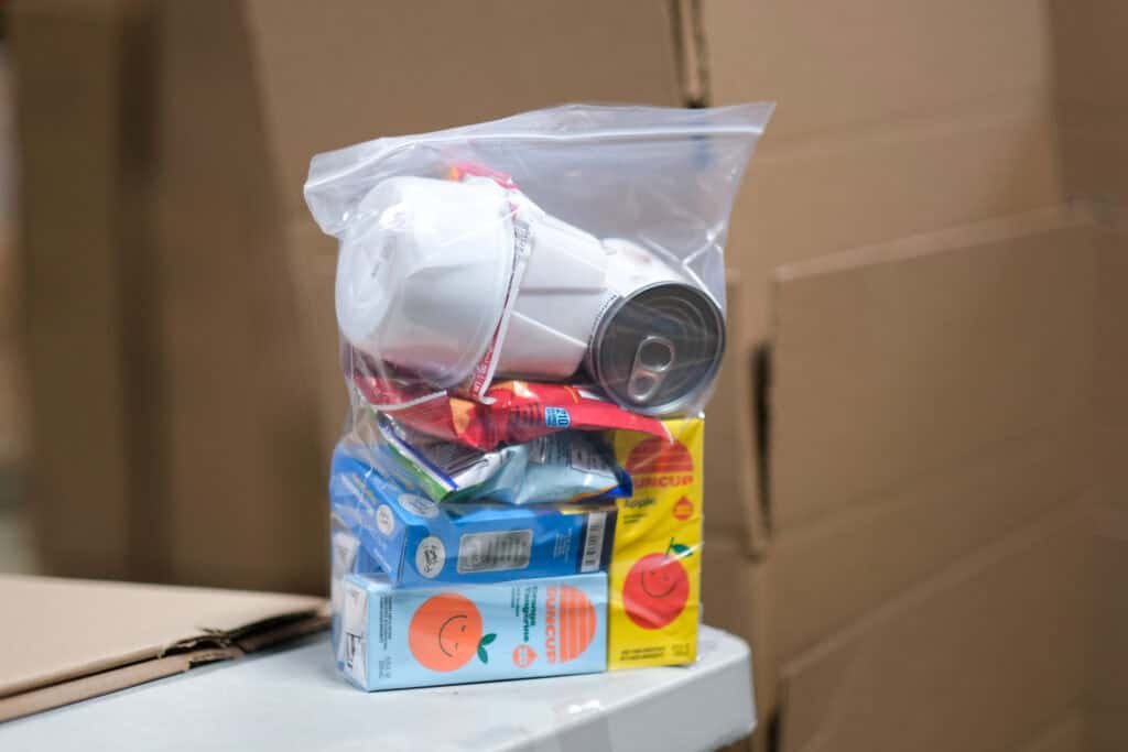  clear plastic bag filled with juice boxes, canned food, cereal, and snacks from the BackPack Program, providing weekend meals for kids in need.