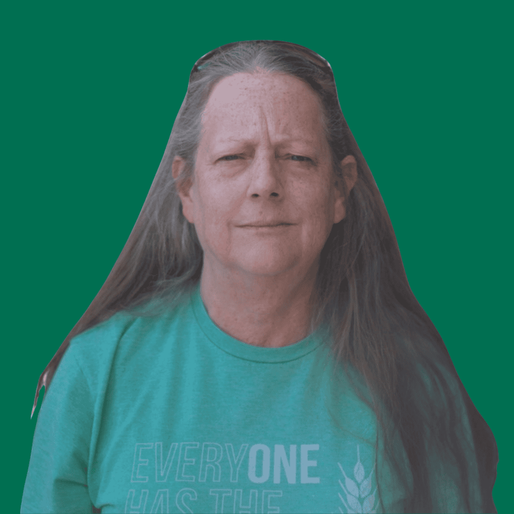 A person with long brown hair and a serious expression wears a green shirt that says EVERYONE HAS THE in white text. The background is a solid teal green.